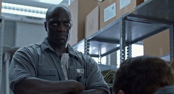 Movie still from “Trumbo” (2015), directed by Jay Roach – A man in grey shirt standing next to boxes in a room; Close Up shot, Over the shoulder angle