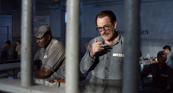 Movie still from “Trumbo” (2015), directed by Jay Roach – A man in a jail cell talking on a cell phone; Medium shot, Over the shoulder angle