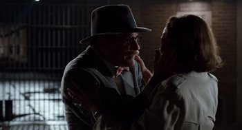 Movie still from “Trumbo” (2015), directed by Jay Roach – An older man in a hat and a tie hugging a woman in a hat; Close Up shot, Over the shoulder angle