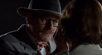 Movie still from “Trumbo” (2015), directed by Jay Roach – An older man wearing a hat and glasses; Close Up shot, Over the shoulder angle