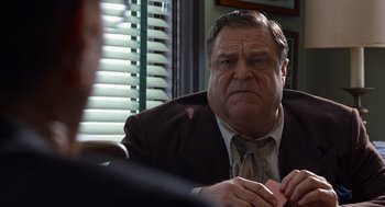 Movie still from “Trumbo” (2015), directed by Jay Roach – An older man sitting at a table in front of another man; Close Up shot, Over the shoulder angle
