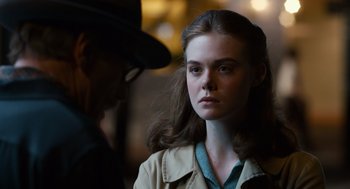 Movie still from “Trumbo” (2015), directed by Jay Roach – A woman in a hat and a jacket looking at the camera; Close Up shot, Over the shoulder angle