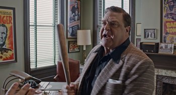 Movie still from “Trumbo” (2015), directed by Jay Roach – An older man holding a baseball bat in a room; Medium shot, Low angle