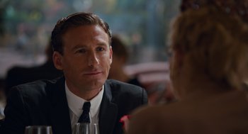 Movie still from “Trumbo” (2015), directed by Jay Roach – A person sitting at a table with a glass of wine; Close Up shot, Over the shoulder angle