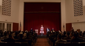 Movie still from “Trumbo” (2015), directed by Jay Roach – A group of people sitting in front of an audience on a stage; Extreme Wide shot, Low angle