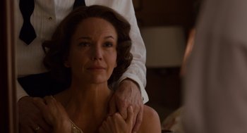 Movie still from “Trumbo” (2015), directed by Jay Roach – A woman sitting on a man's lap in a room; Close Up shot, Over the shoulder angle