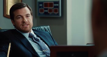 Movie still from “Up in the Air” (2009), directed by Jason Reitman – A man sitting in a chair wearing a suit and tie; Close Up shot, Over the shoulder angle