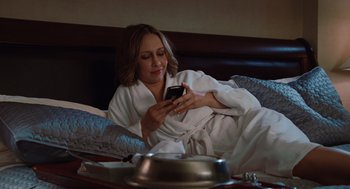 Movie still from “Up in the Air” (2009), directed by Jason Reitman – A woman in a white bathrobe looking at her cell phone; Medium shot, High angle
