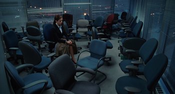 Movie still from “Up in the Air” (2009), directed by Jason Reitman – A woman sitting in a room full of office chairs; Wide shot, High angle