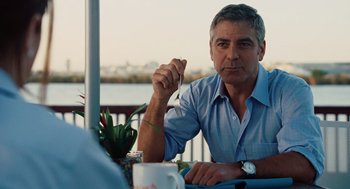 Movie still from “Up in the Air” (2009), directed by Jason Reitman – A man sitting at a table holding a fork in his hand; Close Up shot, Over the shoulder angle