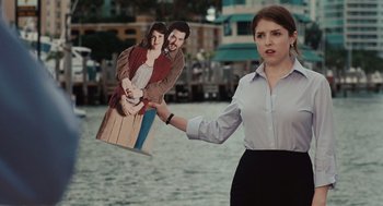 Movie still from “Up in the Air” (2009), directed by Jason Reitman – A woman holding up a cut out of a man and a woman; Medium shot, Over the shoulder angle