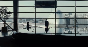 Movie still from “Up in the Air” (2009), directed by Jason Reitman – A man standing in front of an airplane with a suitcase; Extreme Wide shot, Low angle