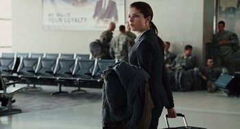 Movie still from “Up in the Air” (2009), directed by Jason Reitman – A woman in a black jacket is holding a bag; Medium shot, Over the shoulder angle