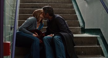 Movie still from “Up in the Air” (2009), directed by Jason Reitman – A man and a woman sitting on steps kissing each other; Medium shot, Low angle