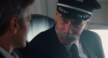 Movie still from “Up in the Air” (2009), directed by Jason Reitman – An older man with a mustache wearing a hat; Close Up shot, Over the shoulder angle
