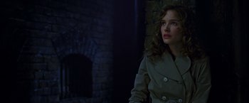 Movie still from “V for Vendetta” (2005), directed by James McTeigue – A woman in a trench coat standing next to a brick wall; Close Up shot, Over the shoulder angle