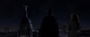 Movie still from “V for Vendetta” (2005), directed by James McTeigue – A man wearing a black hat standing in front of a building; Extreme Wide shot, Low angle