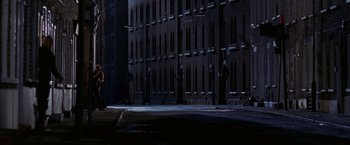 Movie still from “V for Vendetta” (2005), directed by James McTeigue – A person standing on the side of a road near a tall building; Extreme Wide shot, High angle