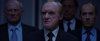 Movie still from “V for Vendetta” (2005), directed by James McTeigue – An older man wearing a suit and tie; Close Up shot, Low angle