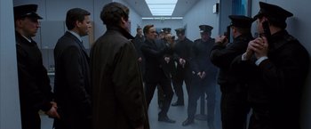 Movie still from “V for Vendetta” (2005), directed by James McTeigue – A group of men standing in a hallway with one man taking a picture; Medium shot, Low angle