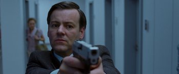 Movie still from “V for Vendetta” (2005), directed by James McTeigue – A man in a suit and tie holding a gun; Close Up shot, Low angle