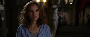 Movie still from “V for Vendetta” (2005), directed by James McTeigue – A beautiful woman with long curly hair standing in the dark; Close Up shot, Over the shoulder angle