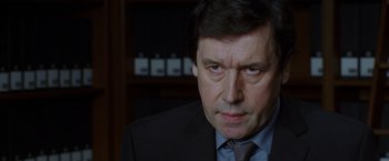 Movie still from “V for Vendetta” (2005), directed by James McTeigue – A person wearing a suit and tie; Close Up shot, Over the shoulder angle