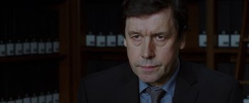 Movie still from “V for Vendetta” (2005), directed by James McTeigue – A person wearing a suit and tie; Close Up shot, Over the shoulder angle