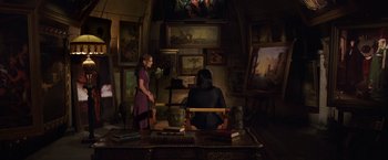 Movie still from “V for Vendetta” (2005), directed by James McTeigue – Two women sitting at a table in front of paintings; Wide shot, High angle