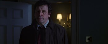 Movie still from “V for Vendetta” (2005), directed by James McTeigue – A man wearing a jacket and tie in a dark room; Close Up shot, Over the shoulder angle