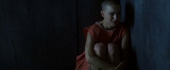 Movie still from “V for Vendetta” (2005), directed by James McTeigue – A woman with shaved head sitting on the ground; Medium shot, High angle
