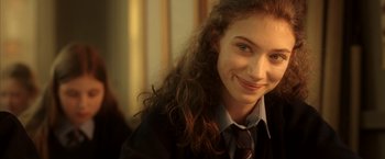 Movie still from “V for Vendetta” (2005), directed by James McTeigue – A young woman with long curly brown hair wearing a tie; Close Up shot, Over the shoulder angle