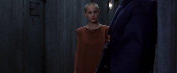 Movie still from “V for Vendetta” (2005), directed by James McTeigue – A woman with a shaved head standing next to a man; Medium shot, Over the shoulder angle