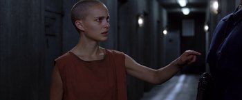 Movie still from “V for Vendetta” (2005), directed by James McTeigue – A woman with a shaved head is standing in a dark room; Close Up shot, Low angle