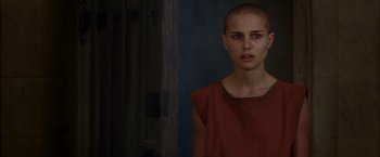 Movie still from “V for Vendetta” (2005), directed by James McTeigue – A woman with a shaved head standing in front of a wall; Close Up shot, Over the shoulder angle