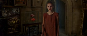 Movie still from “V for Vendetta” (2005), directed by James McTeigue – A woman standing in front of a fish tank in a room; Medium shot, Over the shoulder angle