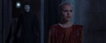 Movie still from “V for Vendetta” (2005), directed by James McTeigue – A woman with a shaved head standing in the rain; Close Up shot, Over the shoulder angle