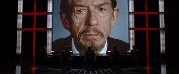 Movie still from “V for Vendetta” (2005), directed by James McTeigue – Three people sitting in front of a large screen; Close Up shot, Over the shoulder angle