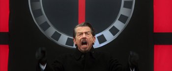 Movie still from “V for Vendetta” (2005), directed by James McTeigue – A man in a black jacket is yelling at the camera; Close Up shot, Low angle