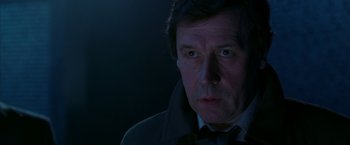 Movie still from “V for Vendetta” (2005), directed by James McTeigue – A person wearing a suit and tie; Close Up shot, Over the shoulder angle