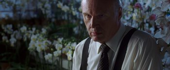 Movie still from “V for Vendetta” (2005), directed by James McTeigue – An older man wearing a suit and a tie; Close Up shot, Low angle