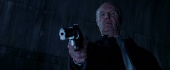 Movie still from “V for Vendetta” (2005), directed by James McTeigue – An older man holding a gun in a dark room; Close Up shot, Low angle