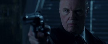 Movie still from “V for Vendetta” (2005), directed by James McTeigue – An older man holding a gun in a dark room; Close Up shot, Low angle