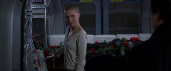 Movie still from “V for Vendetta” (2005), directed by James McTeigue – A woman standing next to a bunch of flowers; Medium shot, Over the shoulder angle