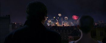 Movie still from “V for Vendetta” (2005), directed by James McTeigue – A man looking at fireworks in the night sky; Medium shot, Over the shoulder angle