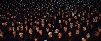 Movie still from “V for Vendetta” (2005), directed by James McTeigue – A large group of people in black shirts and hats; Extreme Wide shot, Overhead angle