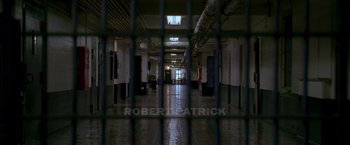 Movie still from “Walk the Line” (2005), directed by James Mangold – A jail cell is seen through bars in a building; Extreme Wide shot, Overhead angle