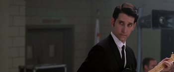 Movie still from “Walk the Line” (2005), directed by James Mangold – A man wearing a suit and tie standing in front of a building; Close Up shot, Low angle