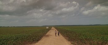 Movie still from “Walk the Line” (2005), directed by James Mangold – Two people walking down a dirt road near a field; Extreme Wide shot, High angle