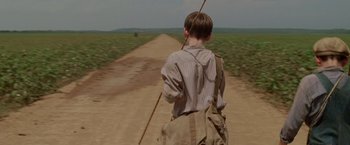 Movie still from “Walk the Line” (2005), directed by James Mangold – A young boy is walking down a dirt road; Medium shot, Over the shoulder angle